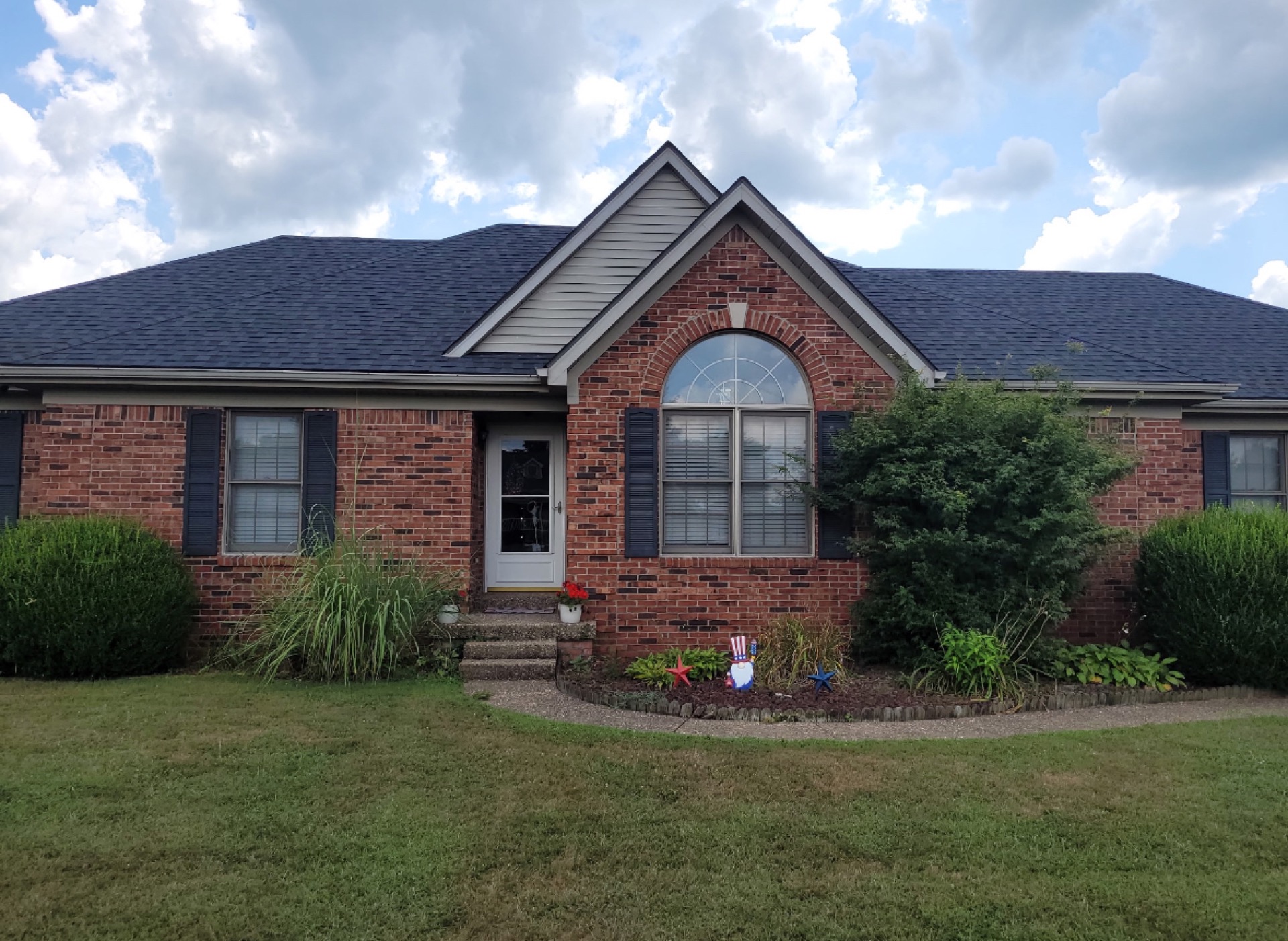 Completed brick ranch home with a new dark architectural shingle roof and landscaped front yard.
